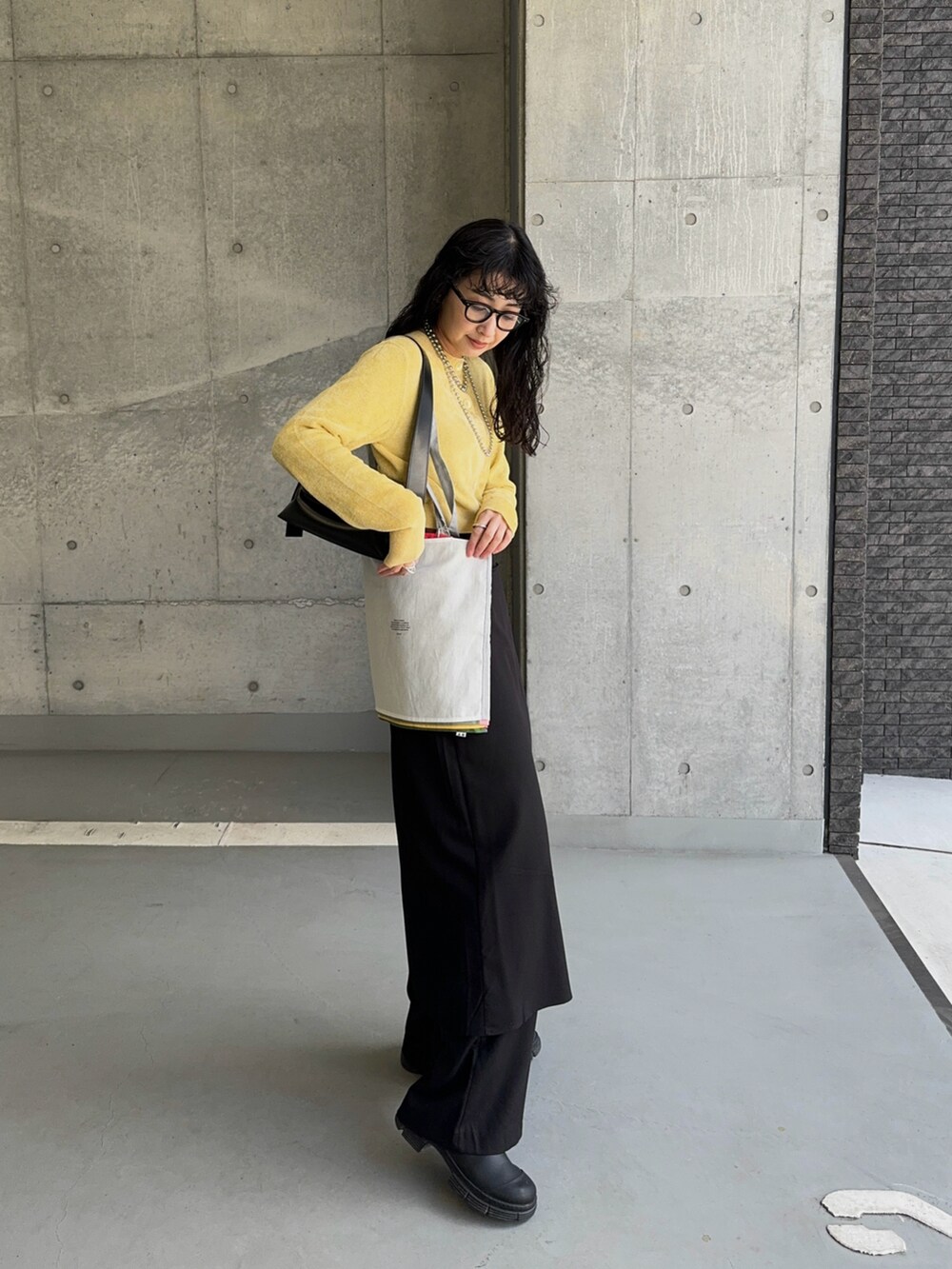 イエロー系のカーディガン/ボレロ、ブラック系のショルダーバッグ、ブラック系のスラックスを着用したレディースの冬コーディネートの3枚目の写真