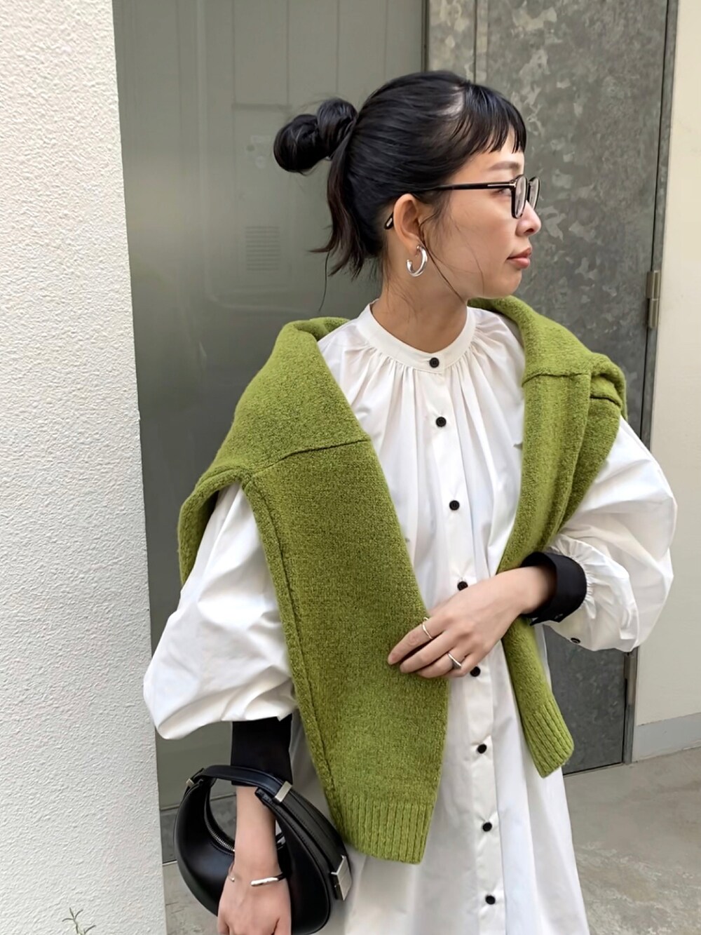 グリーン系のニット/セーター、ホワイト系のシャツワンピース、ブラック系のハンドバッグを着用したレディースの秋コーディネートの2枚目の写真