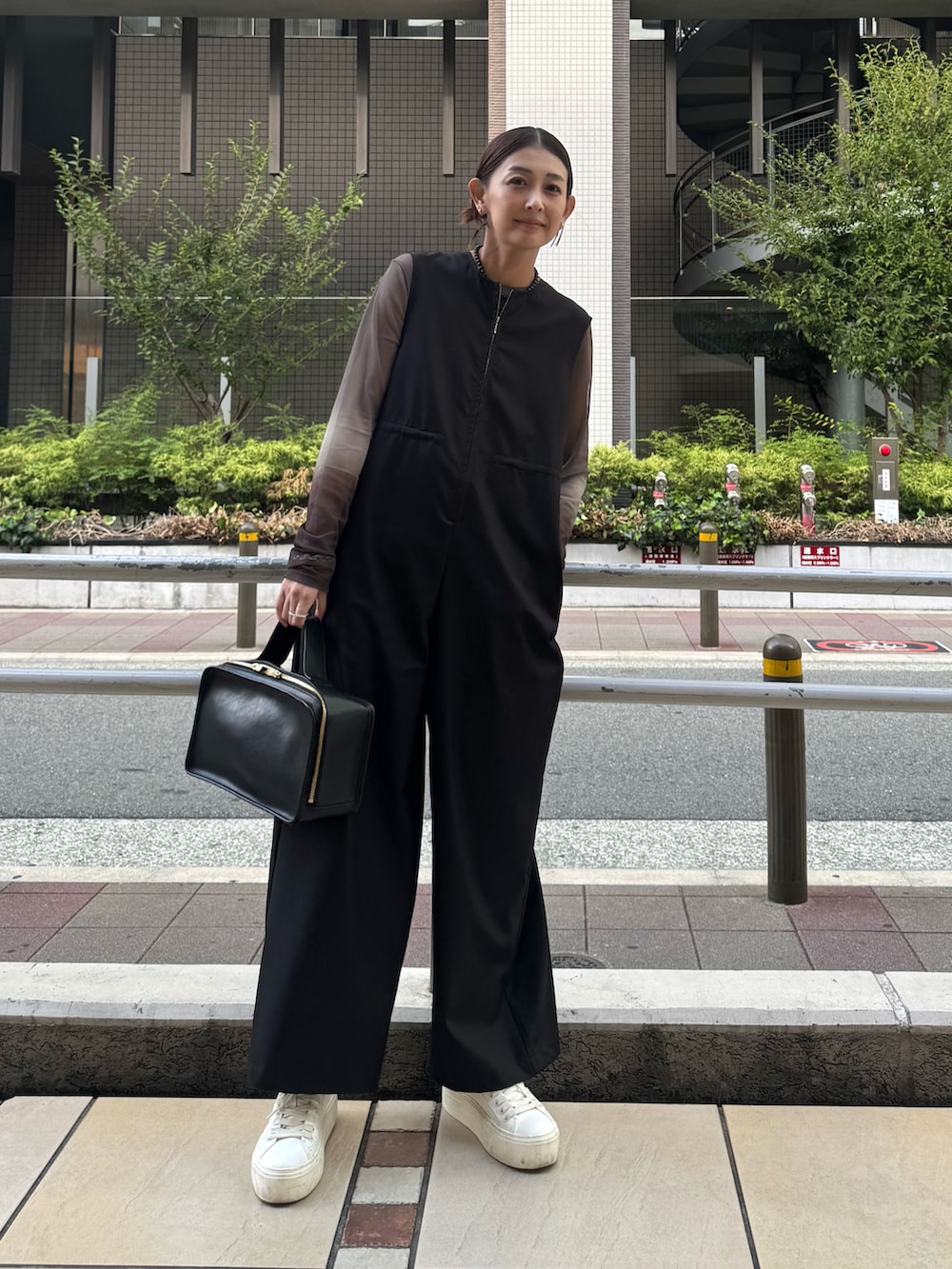 ホワイト系のスニーカー、ブラウン系のTシャツ/カットソー、ブラック系のつなぎ/オールインワンを着用したレディースの秋コーディネートの4枚目の写真