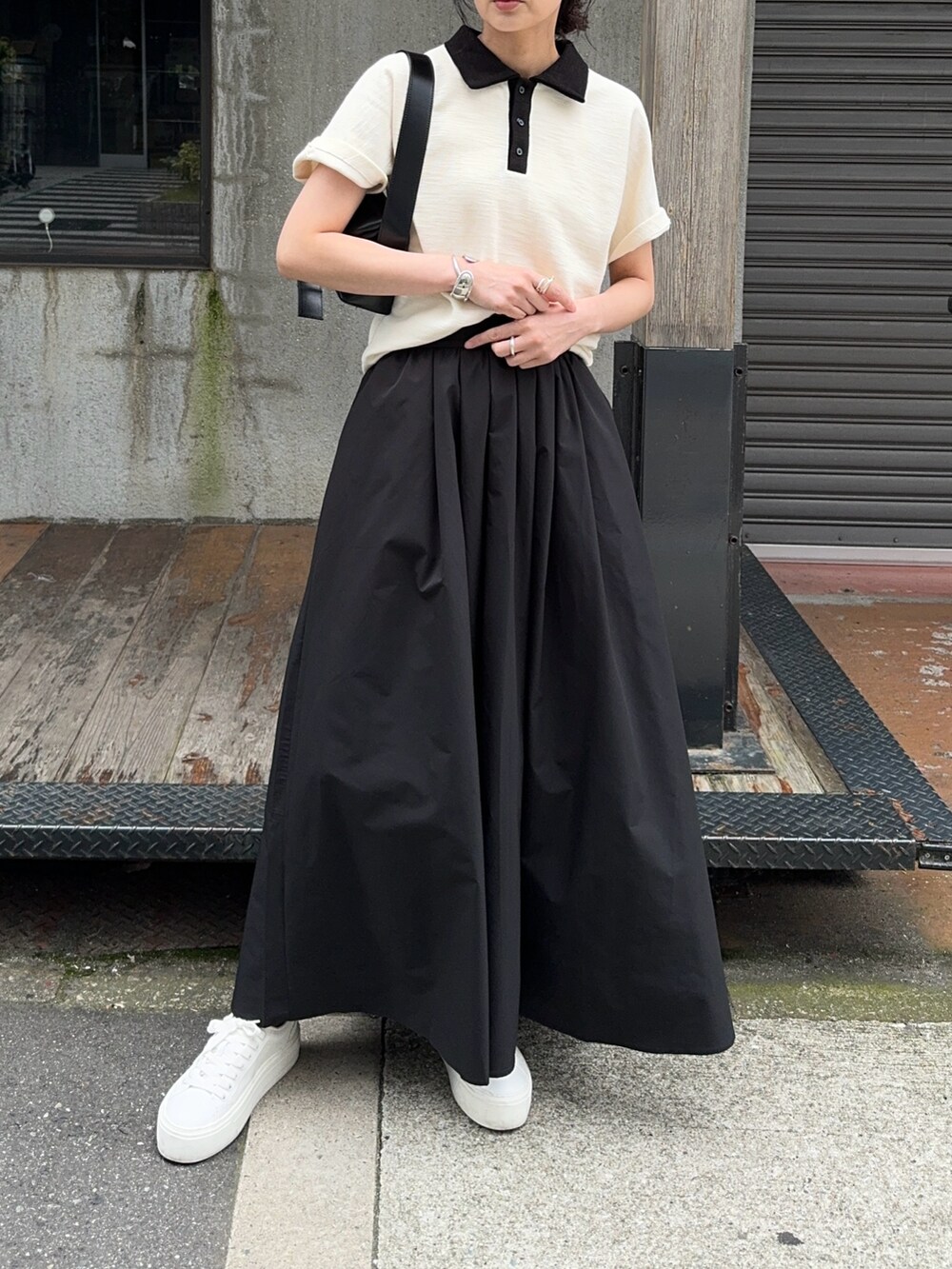 ホワイト系のTシャツ/カットソー、ブラック系のスカート、ホワイト系のスニーカーを着用したレディースの春コーディネートの2枚目の写真