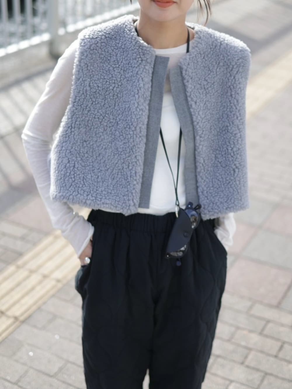 グレー系のベスト、ブラック系のその他パンツ、ブラック系のショルダーバッグを着用したレディースの冬コーディネートの3枚目の写真