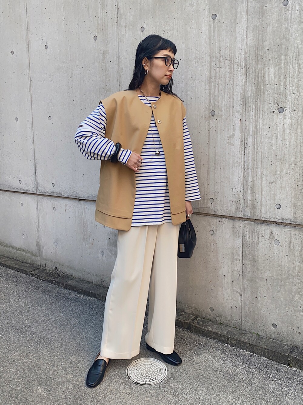 ベージュ系のその他アウター、ブルー系のTシャツ/カットソー、ブラック系のハンドバッグを着用したレディースの春コーディネートの3枚目の写真