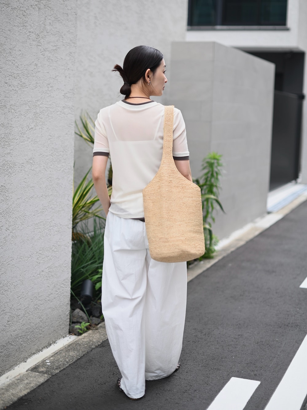 ホワイト系のTシャツ/カットソー、ベージュ系のかごバッグ、ブラウン系のバレエシューズを着用したレディースの夏コーディネートの3枚目の写真