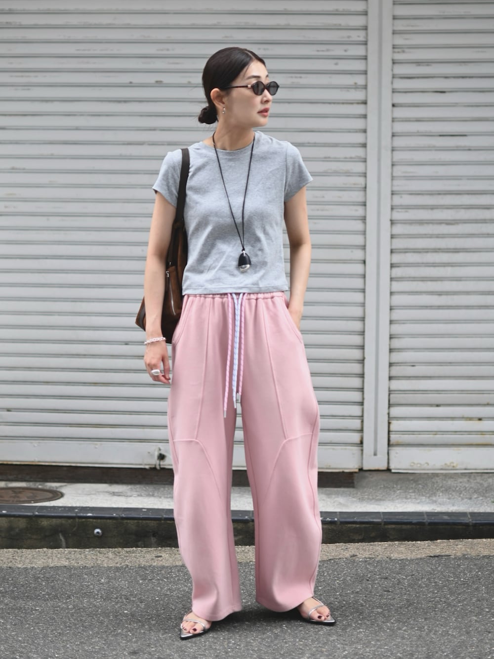 ピンク系のスウェットパンツ、グレー系のTシャツ/カットソー、ブラウン系のトートバッグを着用したレディースの夏コーディネートの2枚目の写真