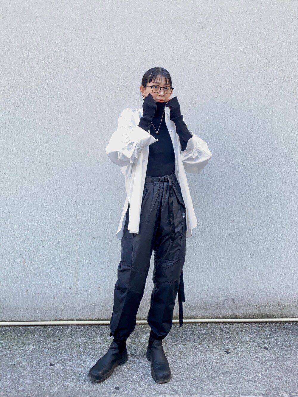 ホワイト系のシャツ/ブラウス、ブラック系のニット/セーター、ブラック系のパンツを着用したレディースの冬コーディネートの2枚目の写真