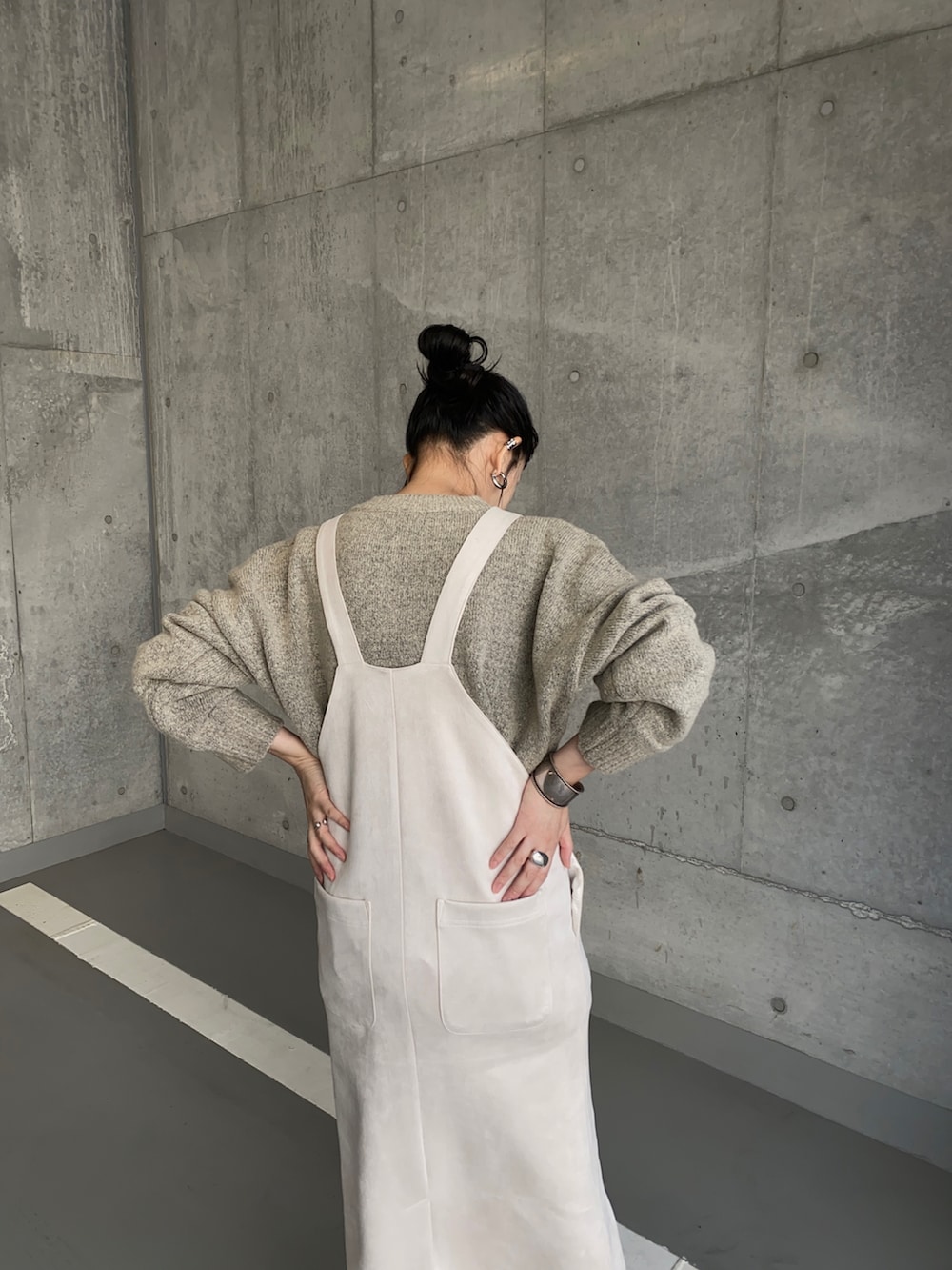 ホワイト系のジャンパースカート、グレー系のニット/セーター、ブラック系のブーツを着用したレディースの秋コーディネートの3枚目の写真