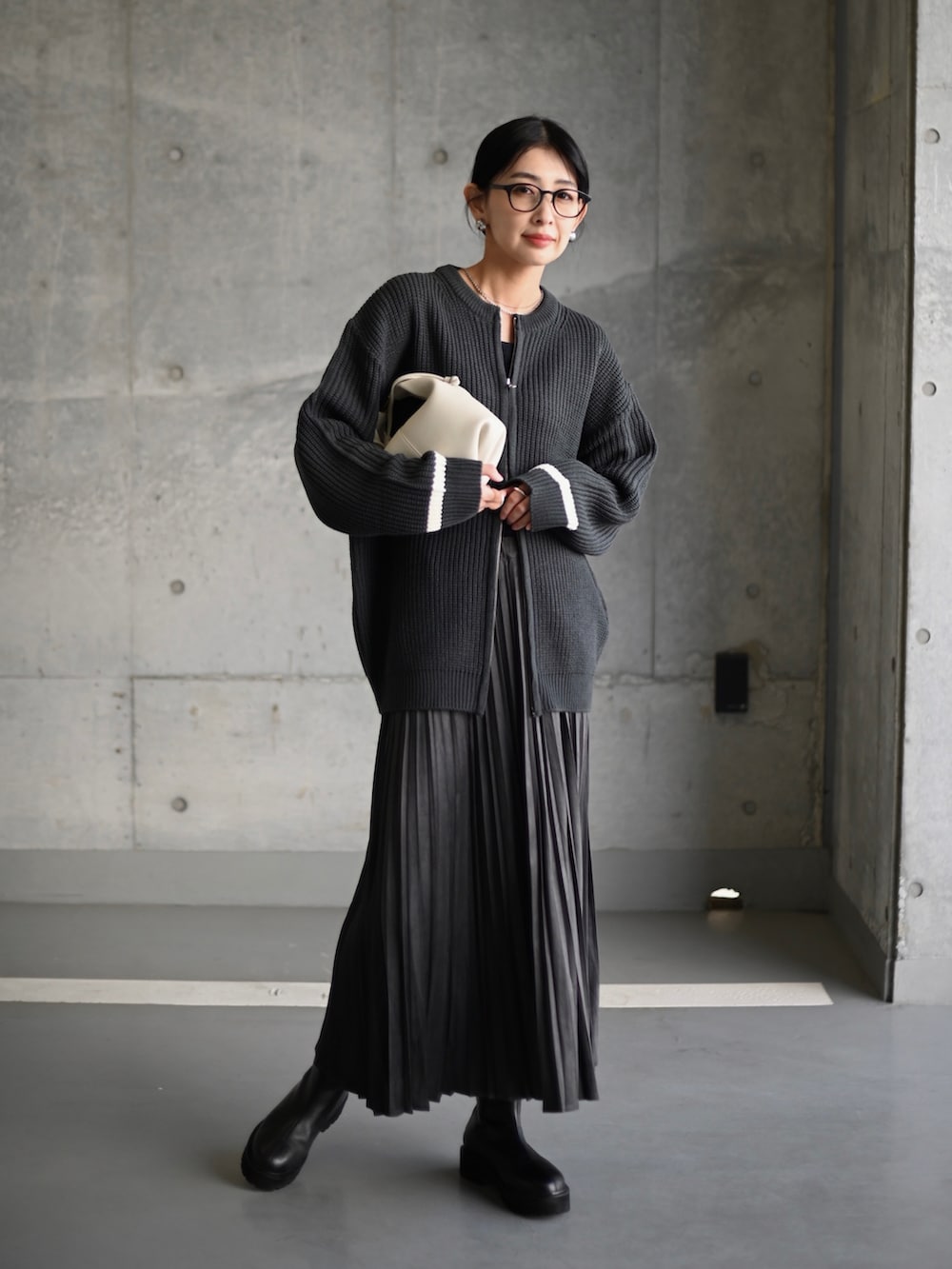 グレー系のスカート、ブラック系のブーツ、ホワイト系のショルダーバッグを着用したレディースの秋コーディネートの5枚目の写真