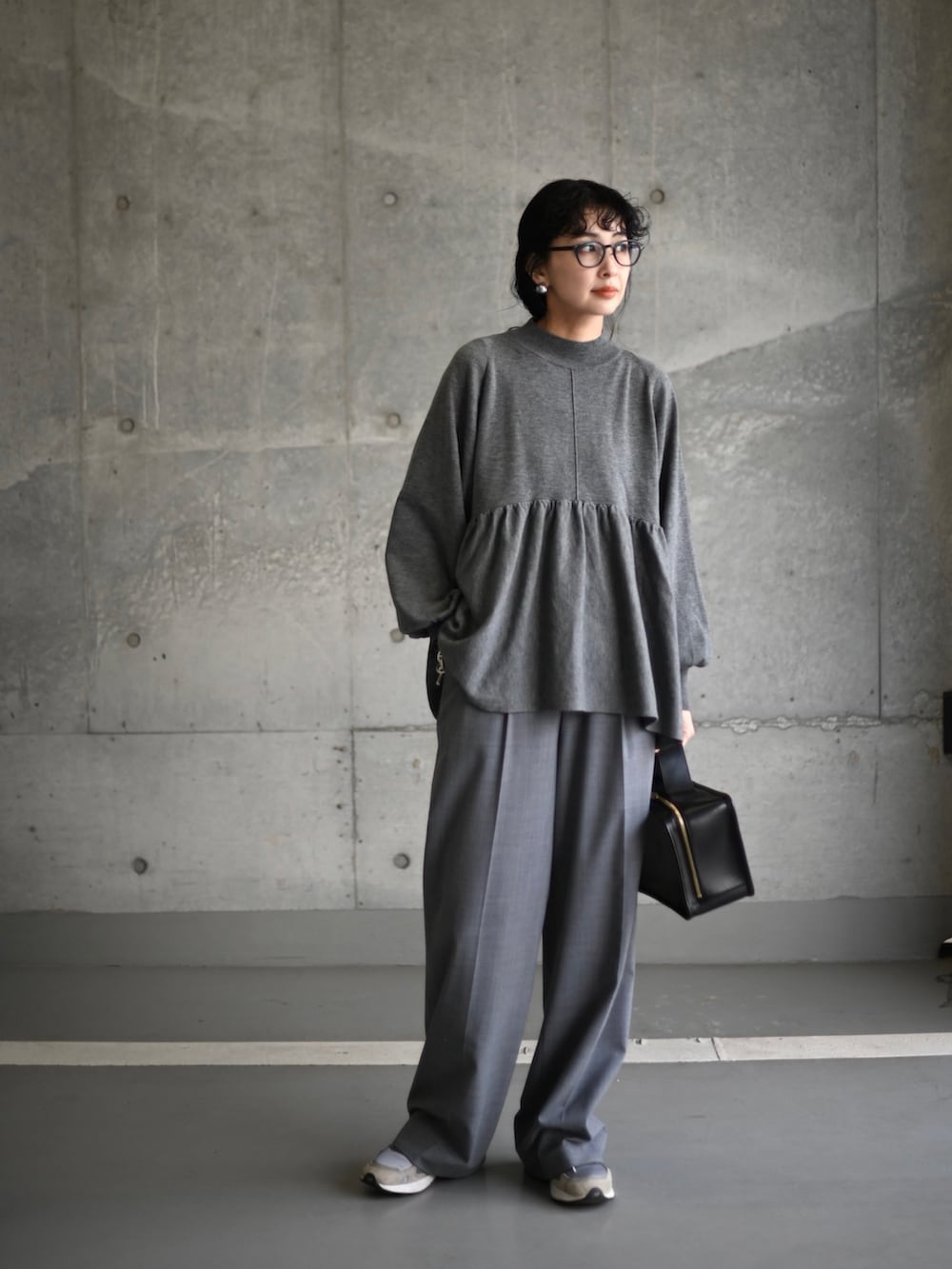 グレー系のニット/セーター、グレー系のスラックス、グレー系のスニーカーを着用したレディースの冬コーディネートの2枚目の写真