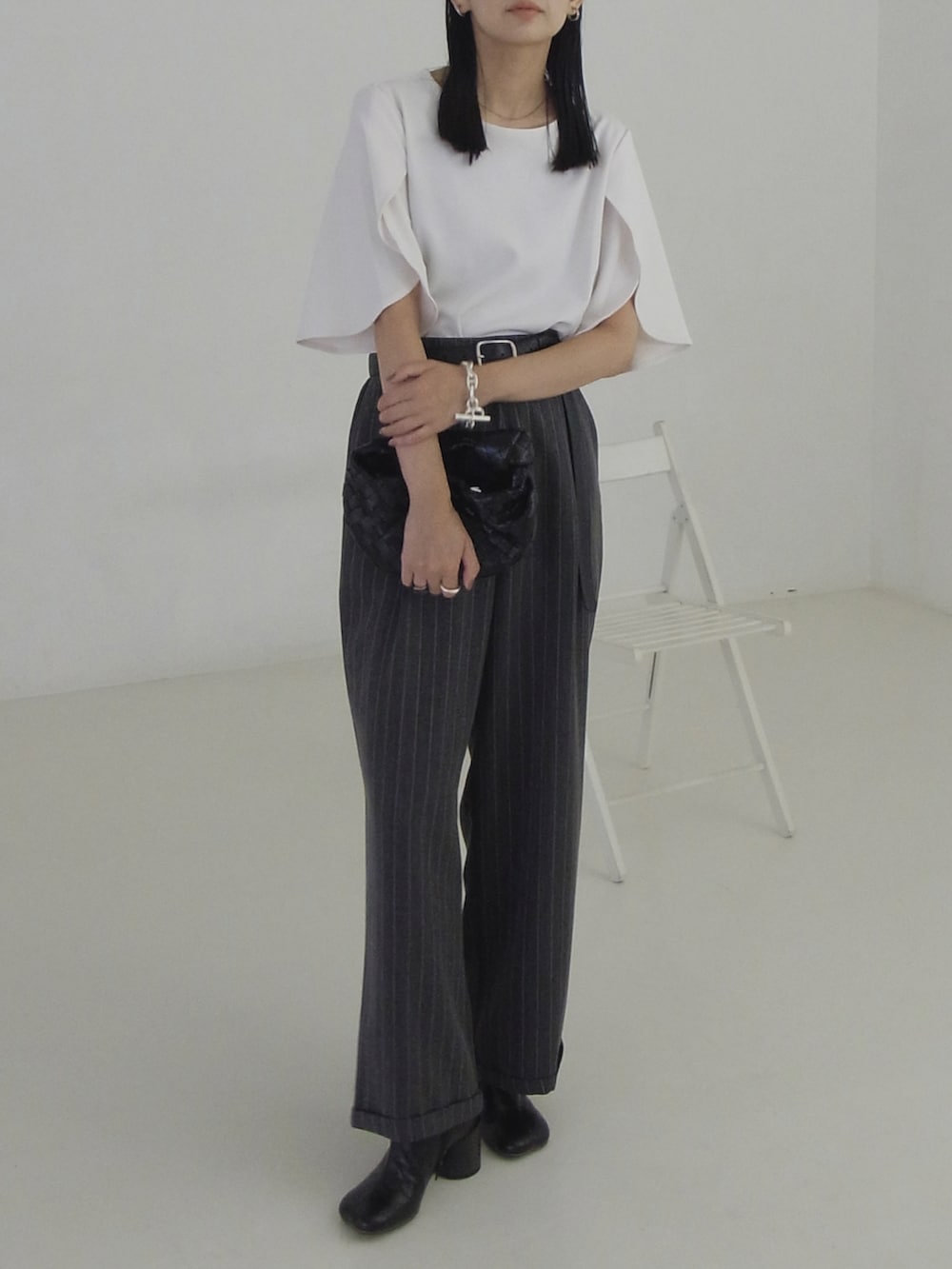 ホワイト系のTシャツ/カットソー、ブラック系のハンドバッグ、ブラック系のブーツを着用したレディースの秋コーディネートの4枚目の写真