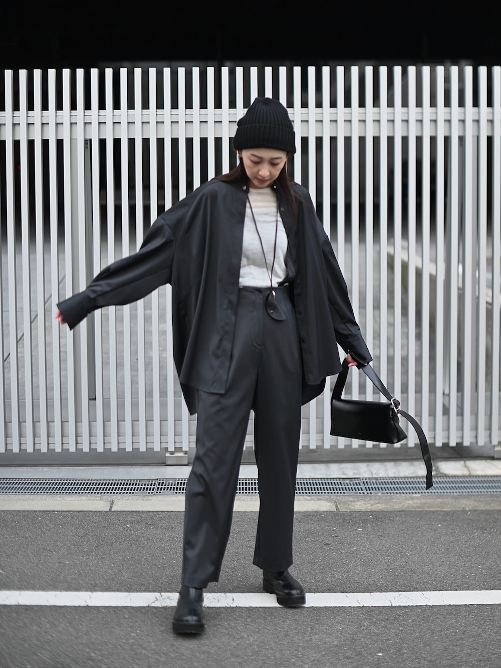 グレー系のシャツ/ブラウス、グレー系のスラックス、ブラック系のショルダーバッグを着用したレディースの冬コーディネートの5枚目の写真