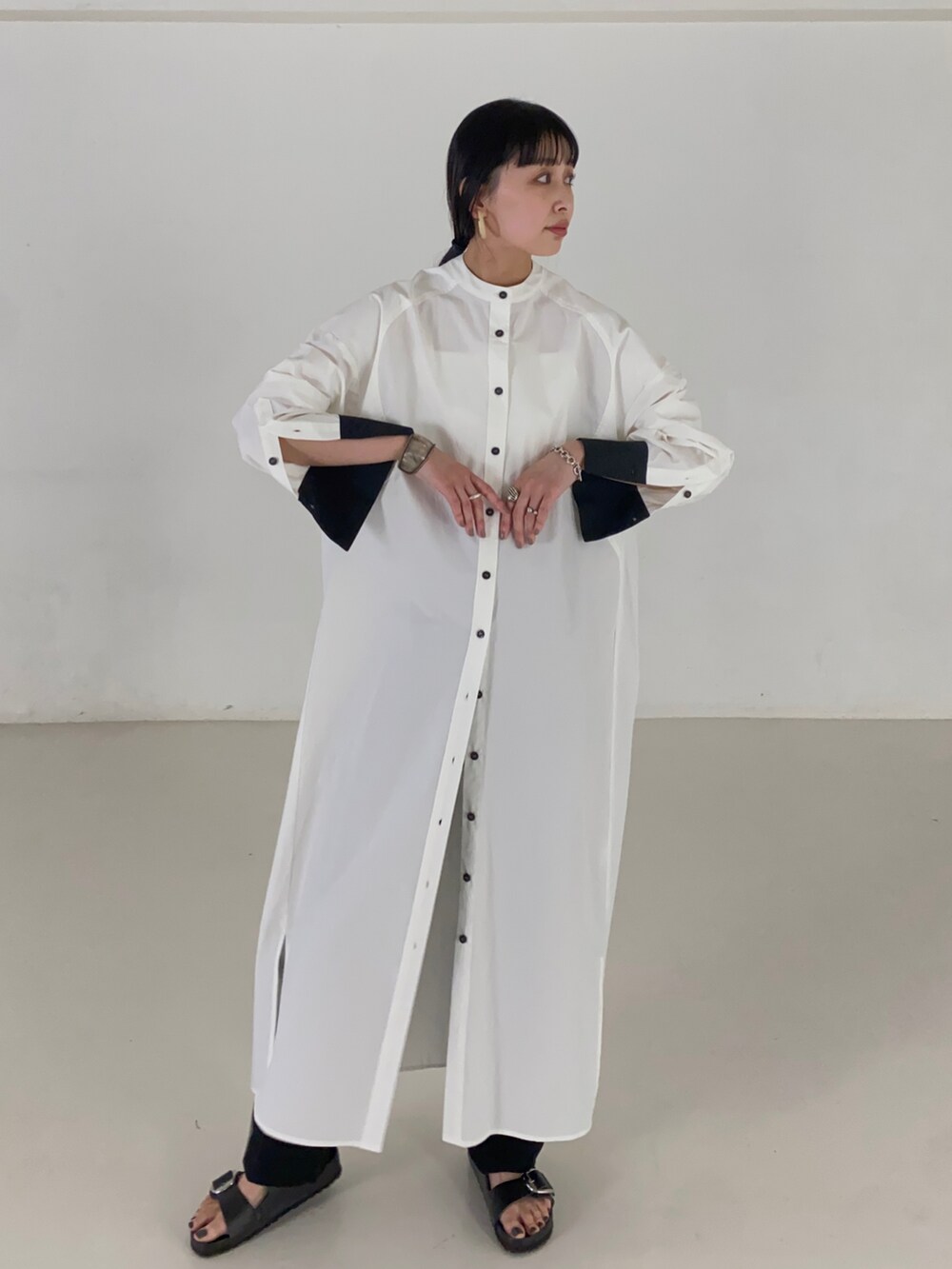 ホワイト系のシャツワンピース、ブラック系のサンダルを着用したレディースの夏コーディネートの2枚目の写真