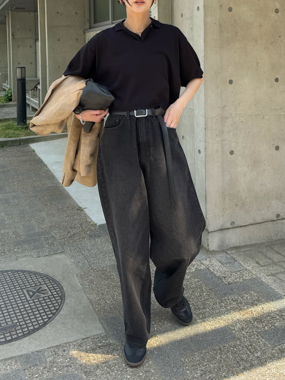 ブラック系のポロシャツ、ブラック系のデニムパンツ、ブラック系のスニーカーを着用したレディースの春コーディネートの4枚目の写真