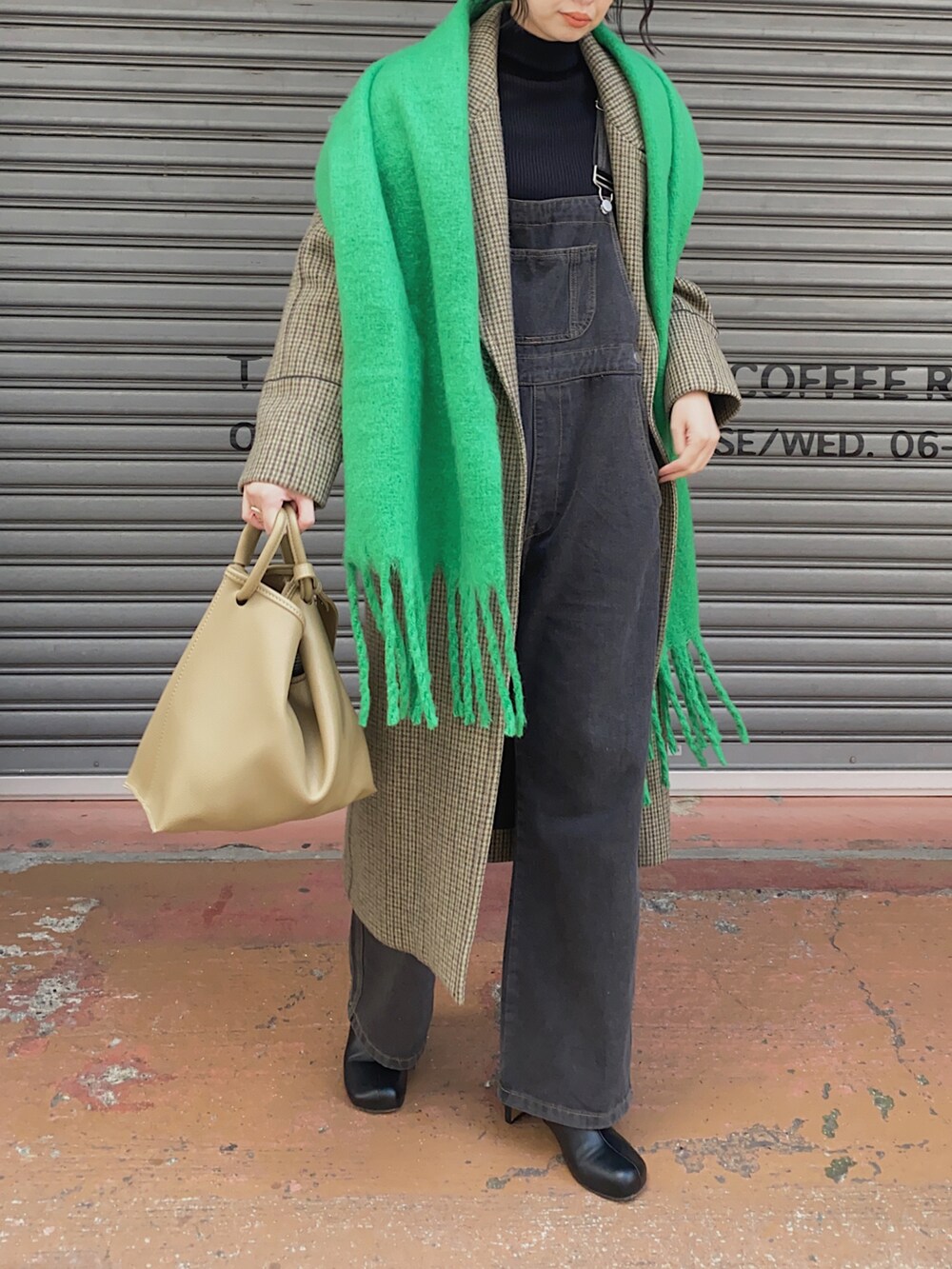 ブラック系のサロペット/オーバーオール、グリーン系のマフラー、ブラック系のメガネを着用したレディースの冬コーディネートの2枚目の写真