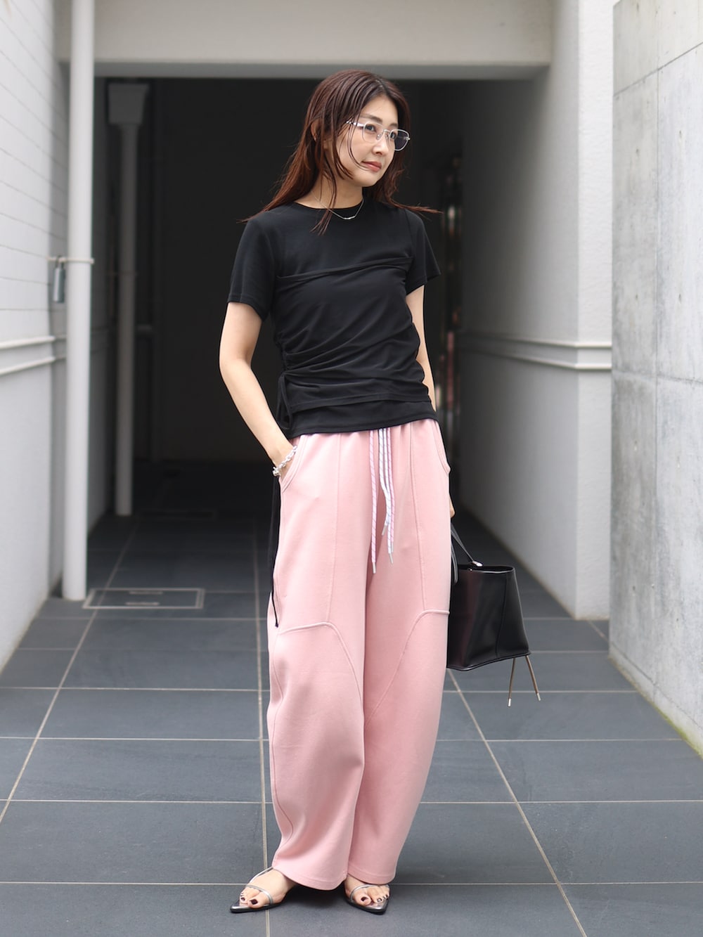 シルバー系のサンダル、ピンク系のスウェットパンツ、ブラック系のトップスを着用したレディースの夏コーディネートの2枚目の写真