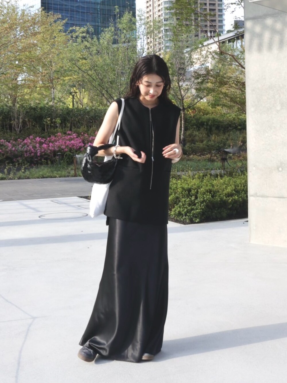 ブラック系のベスト、ホワイト系のトートバッグ、グレー系のスニーカーを着用したレディースの秋コーディネートの3枚目の写真