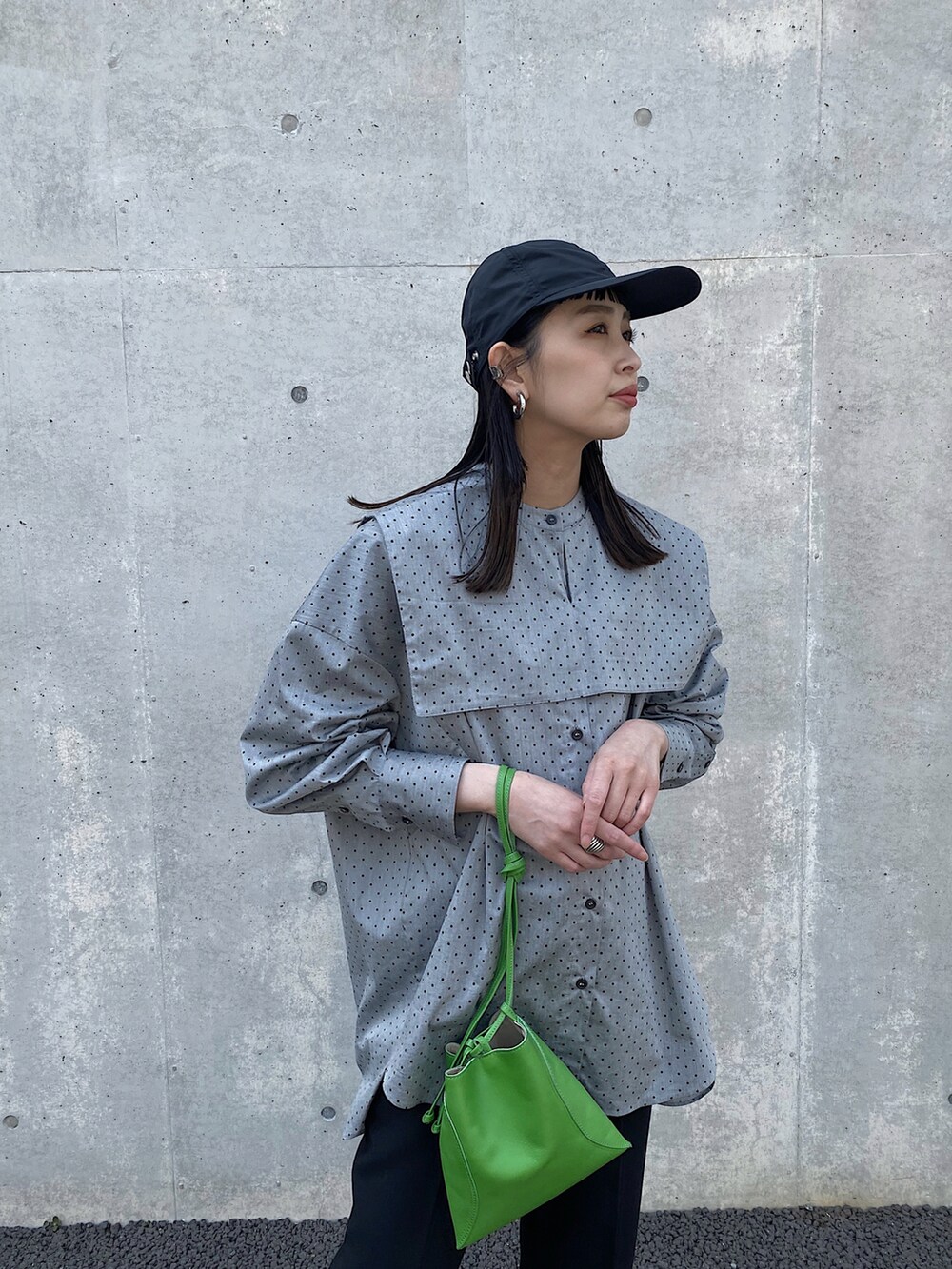 グリーン系のハンドバッグ、ブラック系のスニーカー、ブラック系のシャツ/ブラウスを着用したレディースの春コーディネートの2枚目の写真