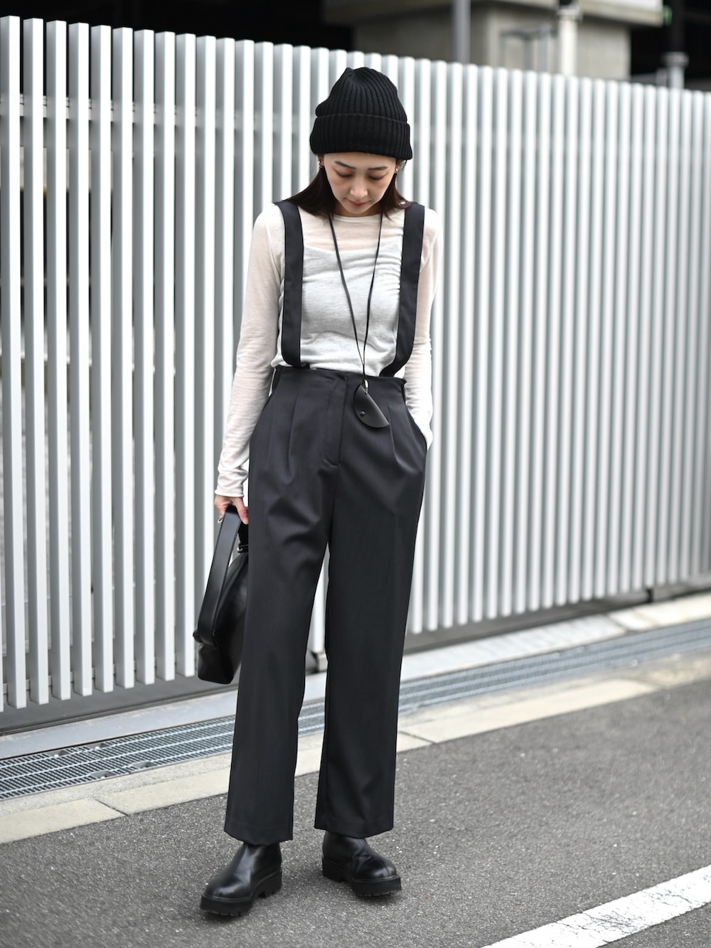 グレー系のスラックス、ブラック系のブーツ、ブラック系のショルダーバッグを着用したレディースの冬コーディネートの5枚目の写真