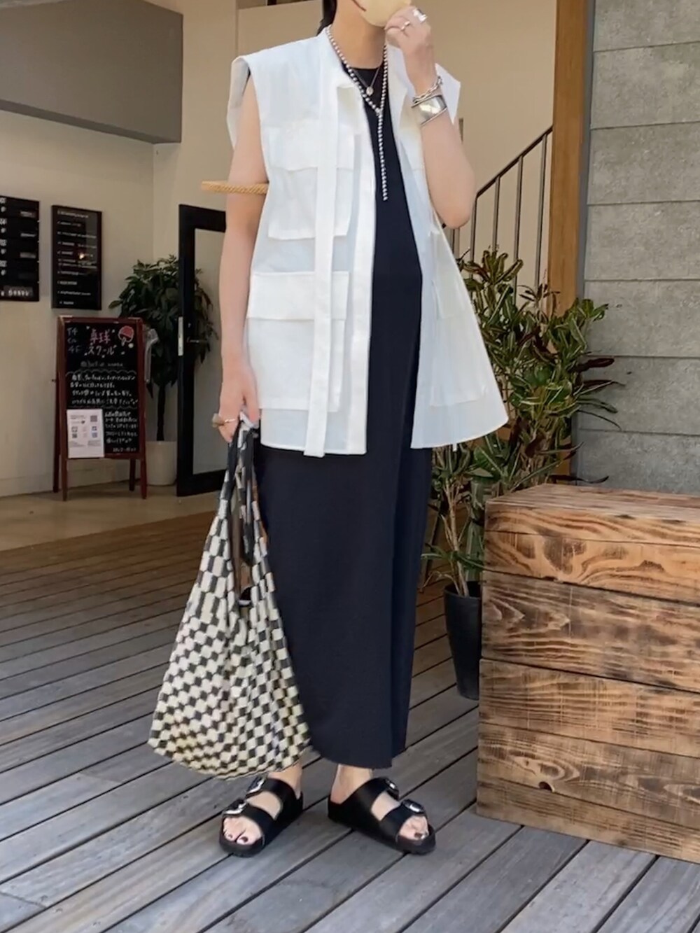 ブラック系のワンピース、ブラック系のサンダル、ブラック系のトートバッグを着用したレディースの夏コーディネートの2枚目の写真