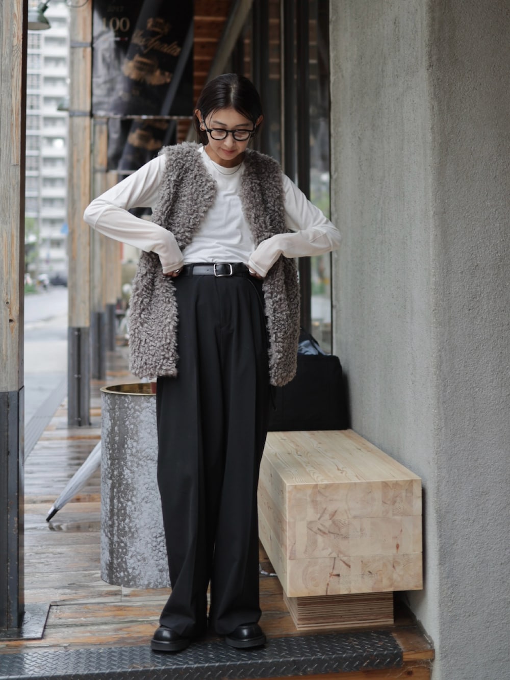 グレー系のベスト、ブラック系のスラックス、ブラック系のローファーを着用したレディースの秋コーディネートの4枚目の写真