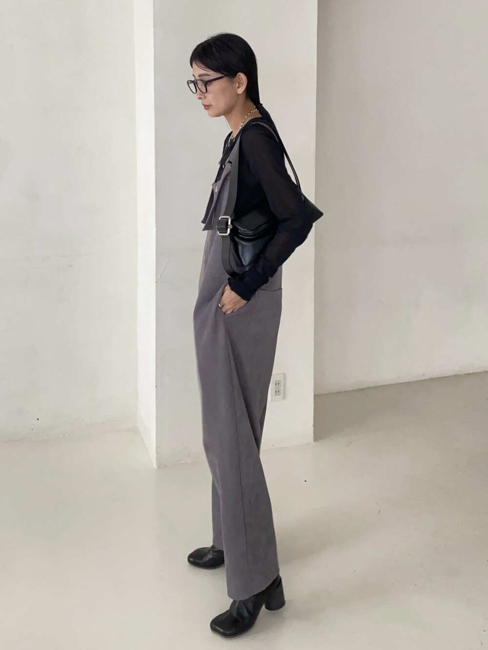 ブラック系のTシャツ/カットソー、グレー系のサロペット/オーバーオール、ブラック系のショルダーバッグを着用したレディースの秋コーディネートの2枚目の写真