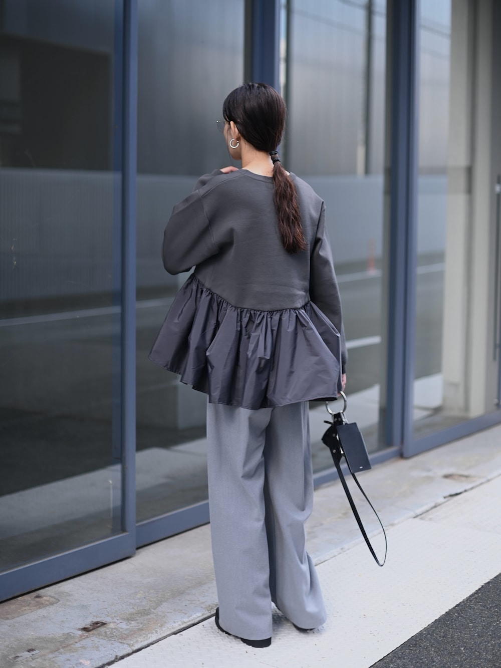 グレー系のニット/セーター、ブラック系のショルダーバッグ、グレー系のスラックスを着用したレディースの秋コーディネートの4枚目の写真