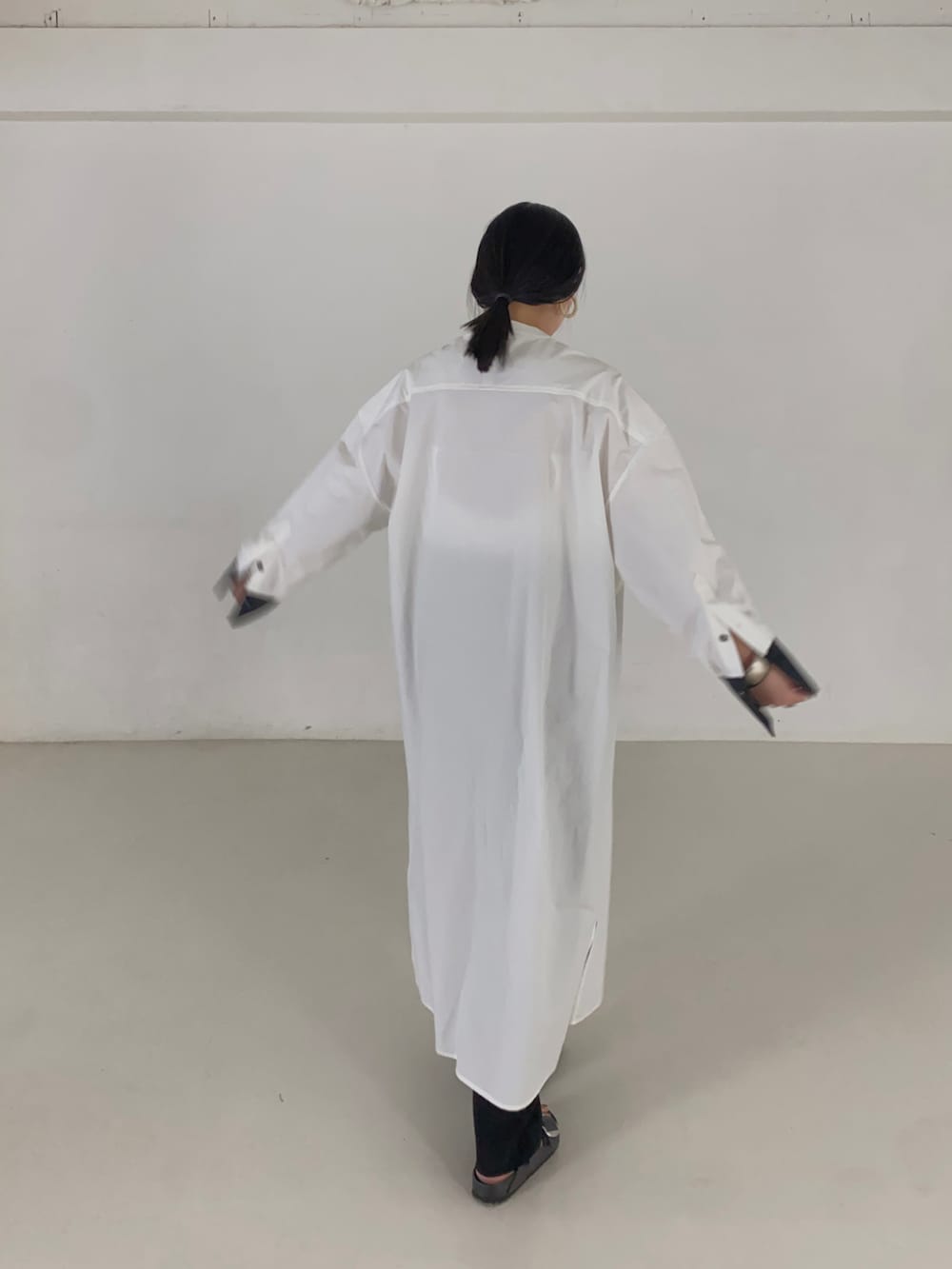 ホワイト系のシャツワンピース、ブラック系のサンダルを着用したレディースの夏コーディネートの3枚目の写真