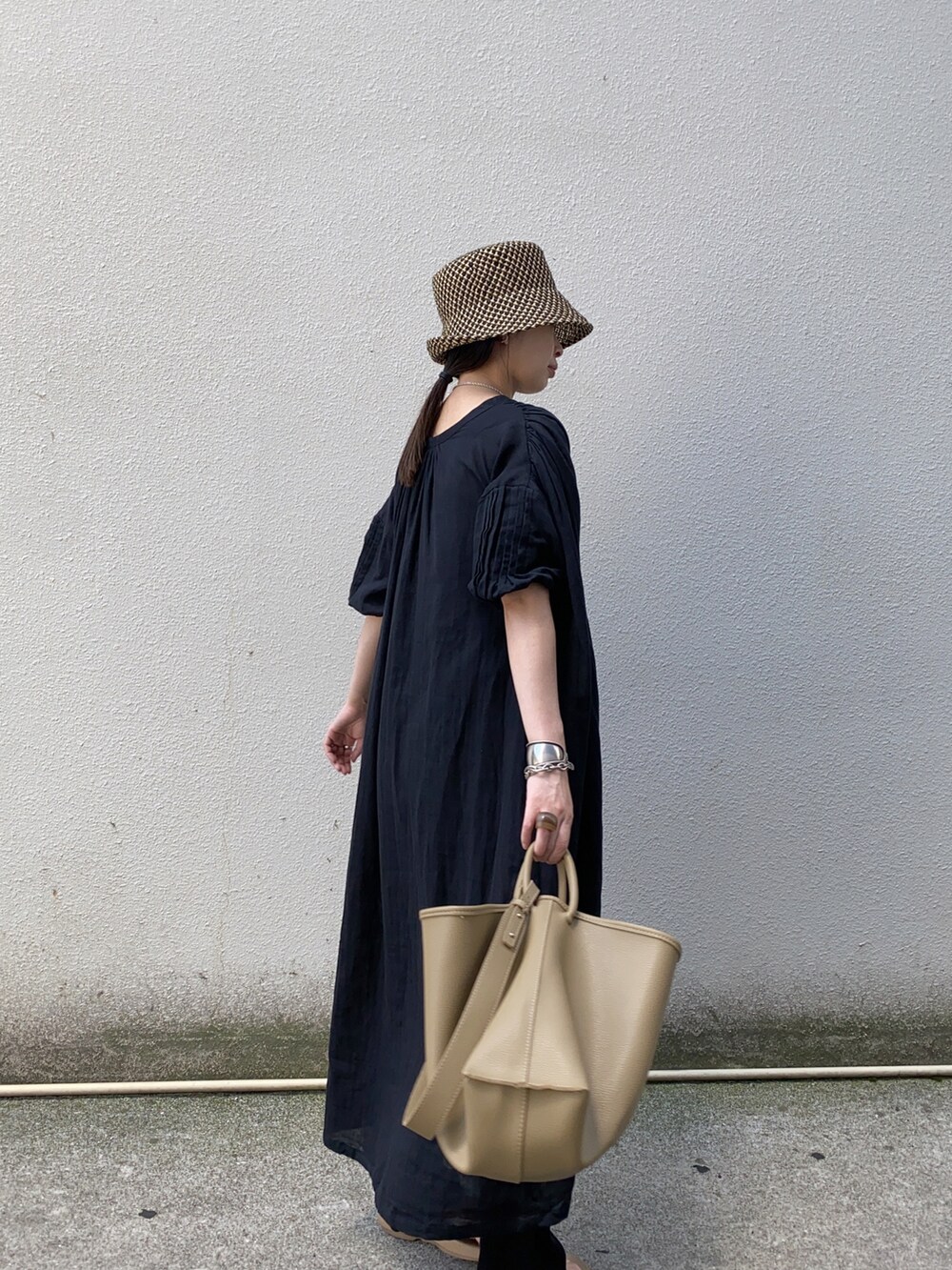 ブラック系のワンピース、ベージュ系のハンドバッグ、ベージュ系のサンダルを着用したレディースの夏コーディネートの3枚目の写真