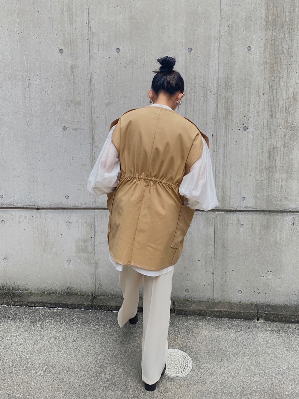 ホワイト系のシャツ/ブラウス、ブラック系のブーツ、ベージュ系のベストを着用したレディースの秋コーディネートの2枚目の写真