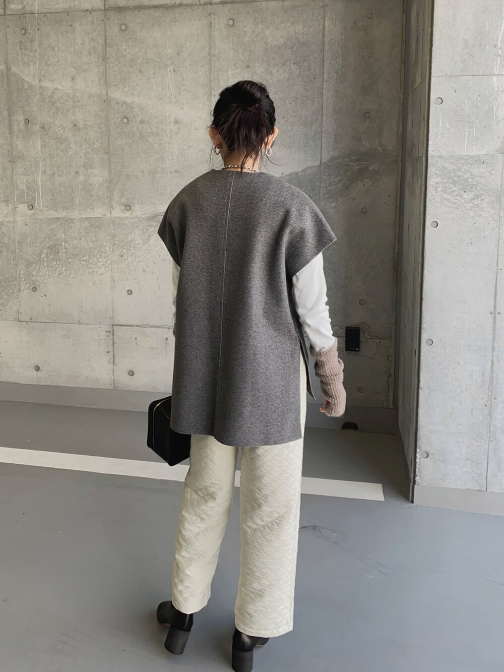 グレー系のベスト、ホワイト系のその他パンツ、ホワイト系のTシャツ/カットソーを着用したレディースの冬コーディネートの2枚目の写真