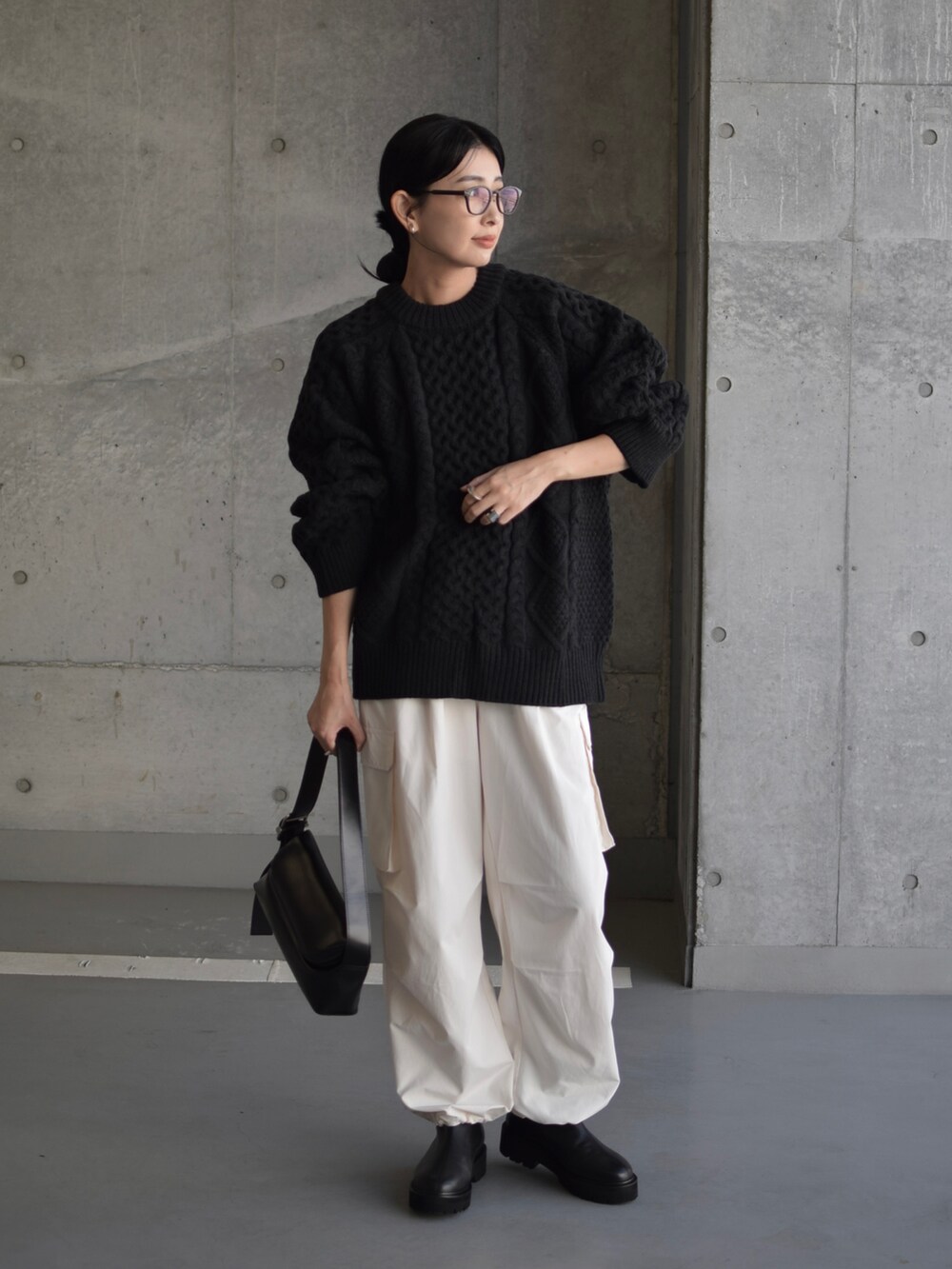 ブラック系のニット/セーター、ブラック系のショルダーバッグ、ブラック系のブーツを着用したレディースの秋コーディネートの5枚目の写真