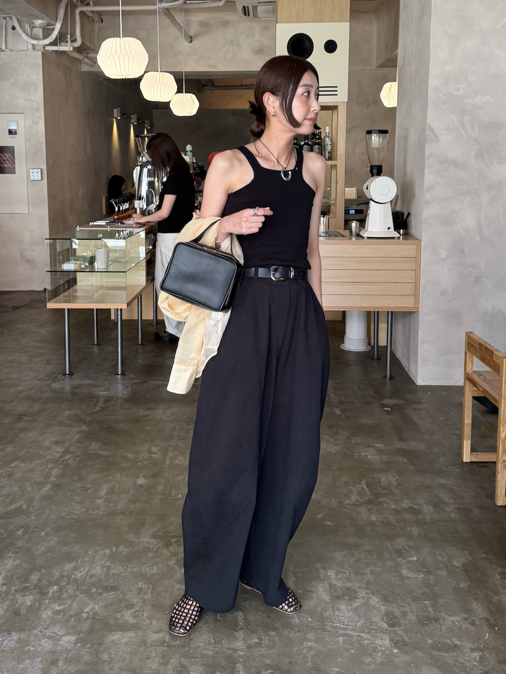 ブラック系のタンクトップ、ブラウン系のバレエシューズ、ブラック系のチノパンツを着用したレディースの秋コーディネートの3枚目の写真