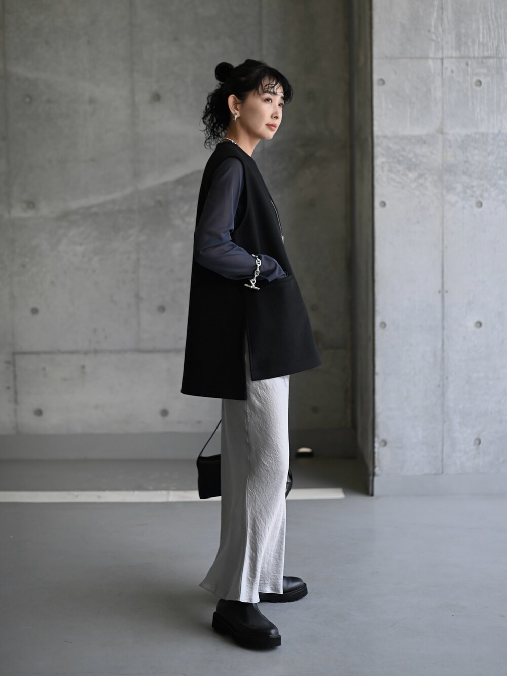 グレー系のTシャツ/カットソー、ブラック系のベスト、シルバー系のスカートを着用したレディースの秋コーディネートの2枚目の写真