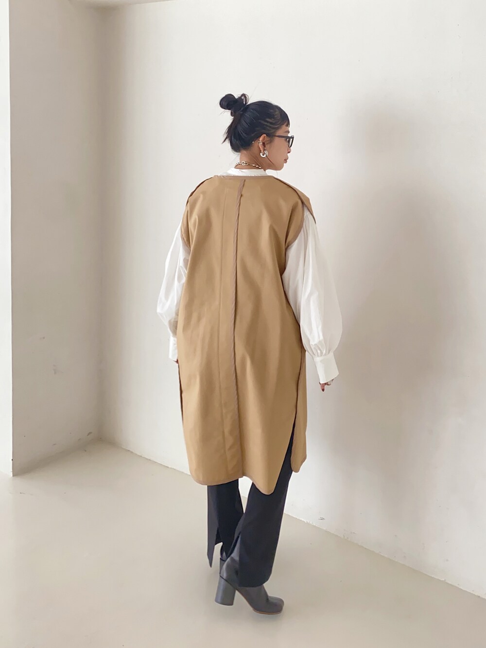 ベージュ系のその他アウター、ホワイト系のシャツ/ブラウス、ブラック系のブーツを着用したレディースの秋コーディネートの2枚目の写真