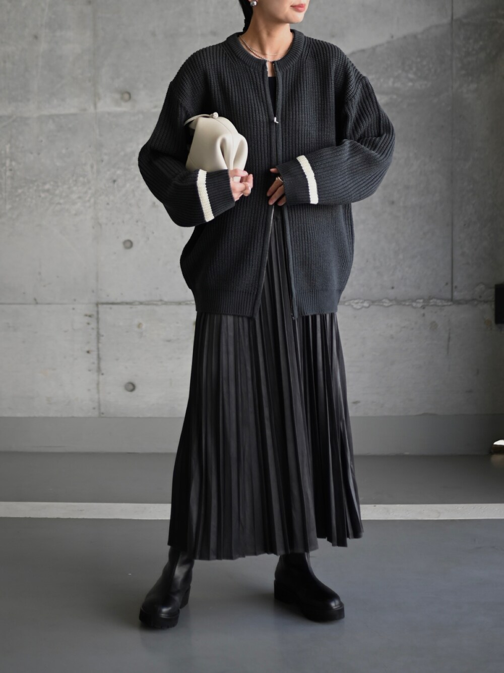 グレー系のスカート、ブラック系のブーツ、ホワイト系のショルダーバッグを着用したレディースの秋コーディネートの2枚目の写真