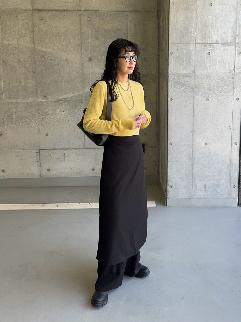 イエロー系のカーディガン/ボレロ、ブラック系のショルダーバッグ、ブラック系のスラックスを着用したレディースの冬コーディネートの5枚目の写真