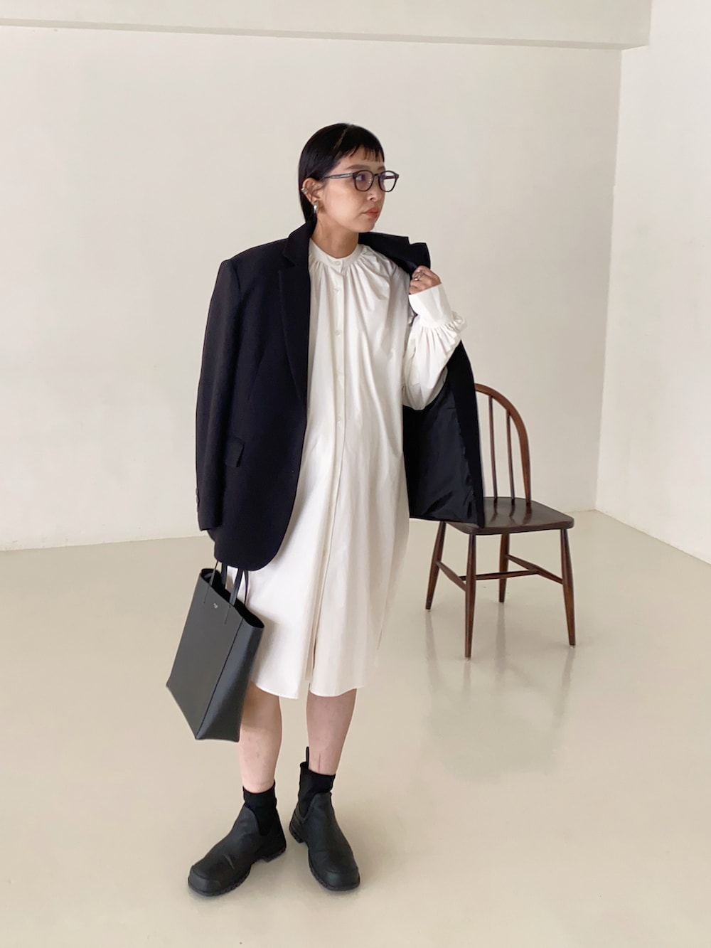 ブラック系のテーラードジャケット、ホワイト系のシャツワンピース、ブラック系のバッグを着用したレディースの秋コーディネートの2枚目の写真