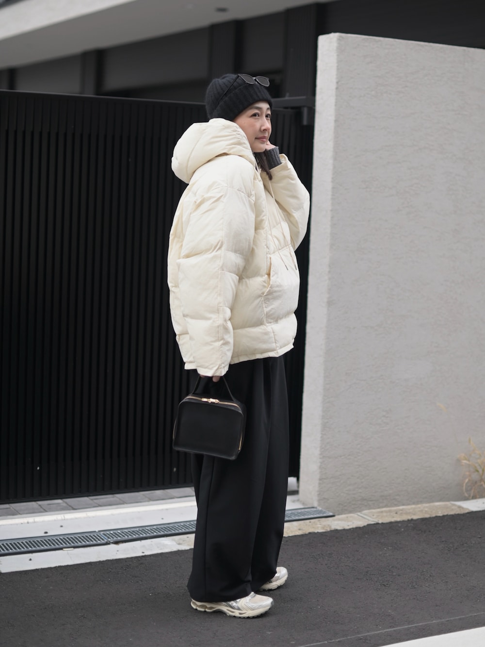 ブラック系のダウンジャケット/コート、シルバー系のスニーカー、ブラック系のサングラスを着用したレディースの冬コーディネートの2枚目の写真