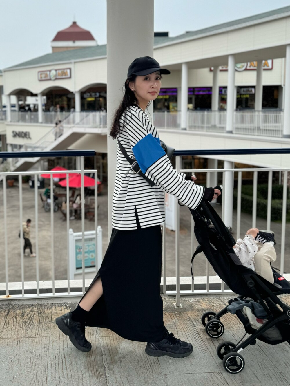 ブルー系のTシャツ/カットソー、ブラック系のスカート、ブラック系のスニーカーを着用したレディースの春コーディネートの2枚目の写真