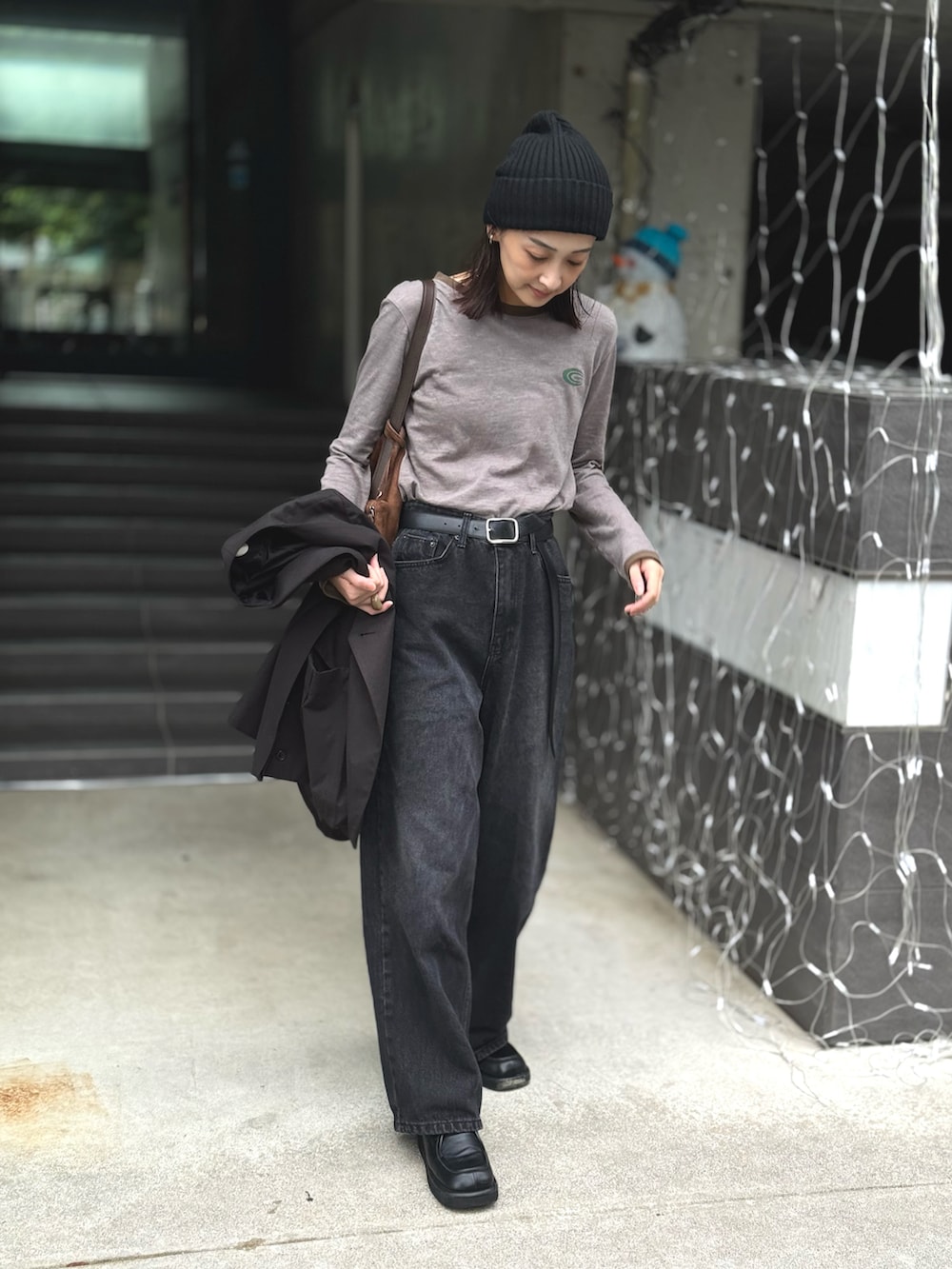 グレー系のTシャツ/カットソー、ブラック系のデニムパンツ、ブラウン系のショルダーバッグを着用したレディースの秋コーディネートの4枚目の写真