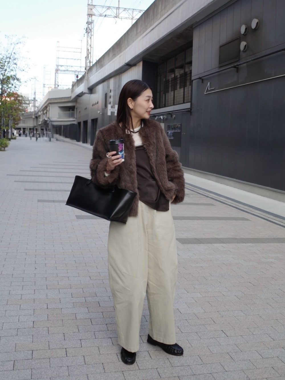 ベージュ系のチノパンツ、ブラウン系のノーカラージャケット、ブラック系のトートバッグを着用したレディースの秋コーディネートの4枚目の写真