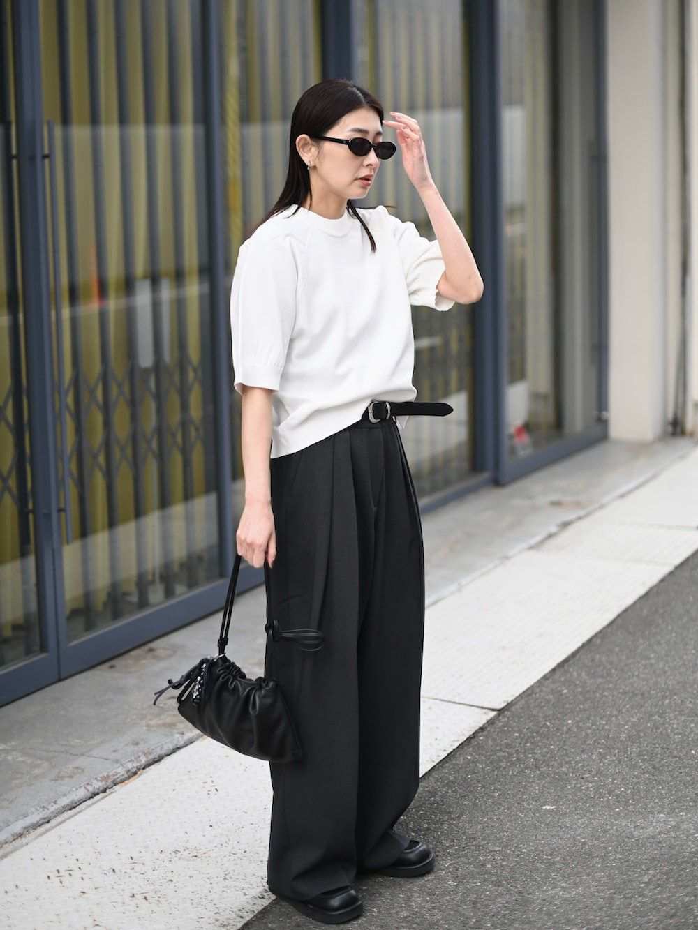 ホワイト系のニット/セーター、グレー系のその他パンツ、ブラック系のローファーを着用したレディースの夏コーディネートの2枚目の写真