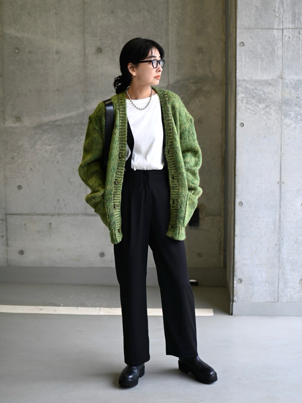 グリーン系のニット/セーター、ブラック系のスラックス、ブラック系のブーツを着用したレディースの冬コーディネートの5枚目の写真