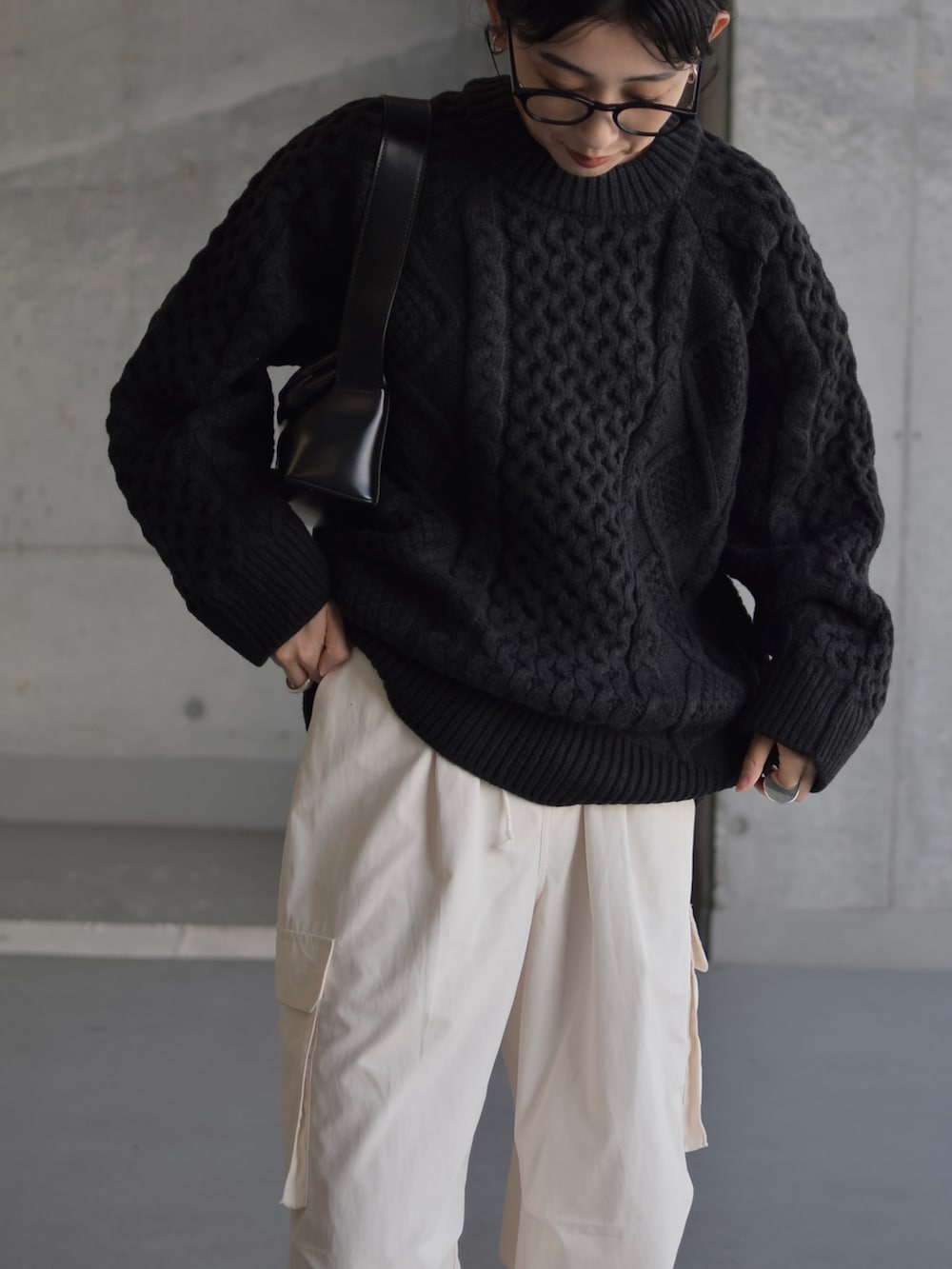 ブラック系のニット/セーター、ブラック系のショルダーバッグ、ブラック系のブーツを着用したレディースの秋コーディネートの3枚目の写真