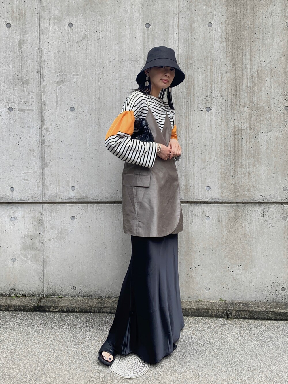 オレンジ系のTシャツ/カットソー、ベージュ系のキャミソール、ブラック系のスカートを着用したレディースの春コーディネートの3枚目の写真