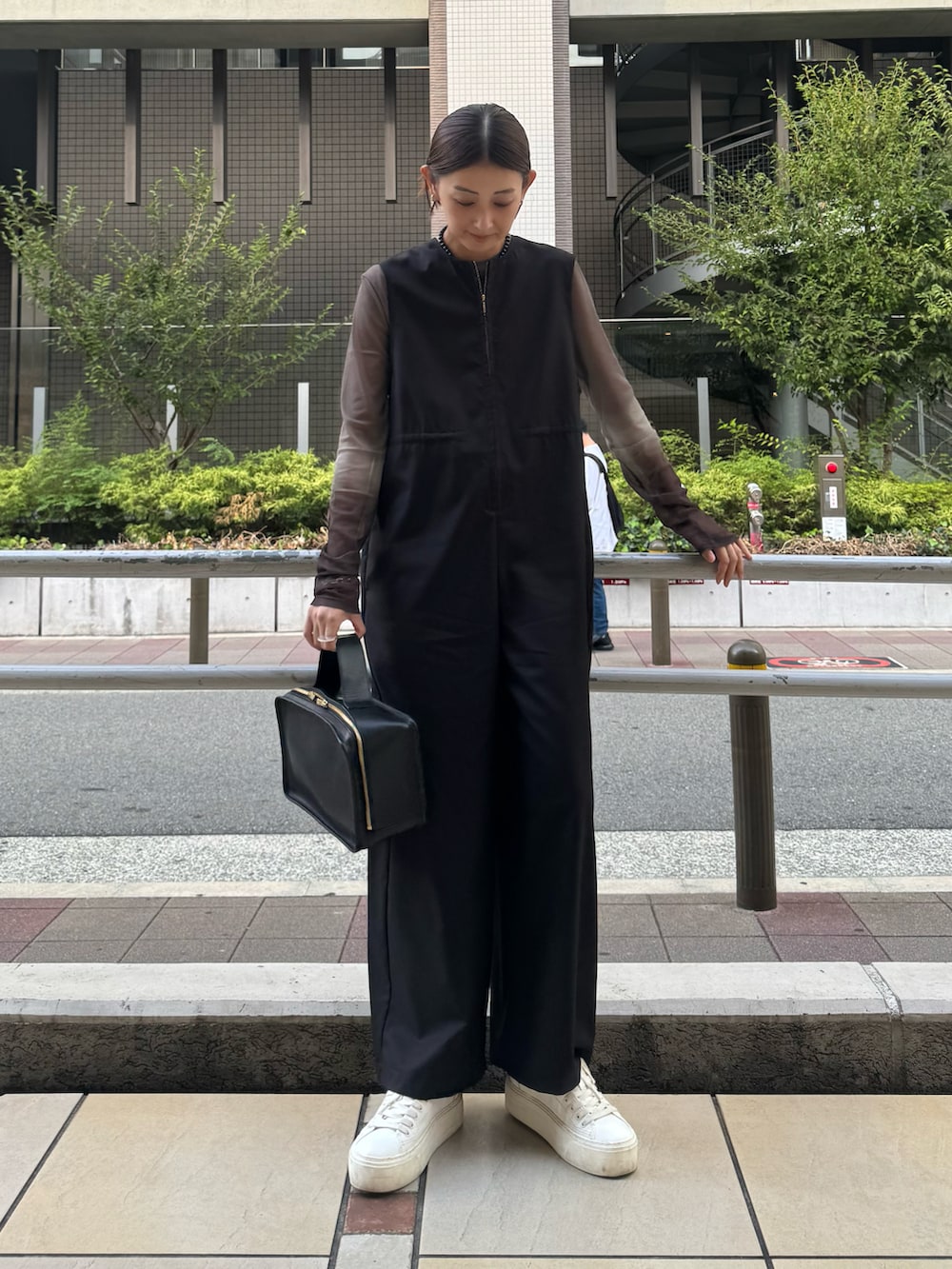 ホワイト系のスニーカー、ブラウン系のTシャツ/カットソー、ブラック系のつなぎ/オールインワンを着用したレディースの秋コーディネートの3枚目の写真