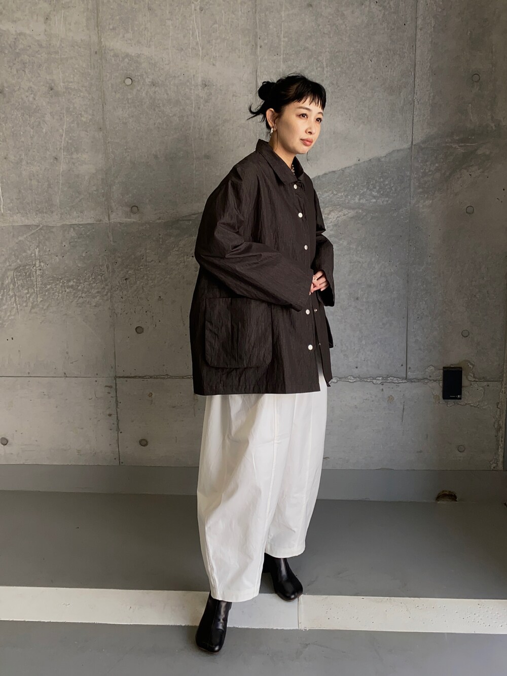 ブラック系のナイロンジャケット、ホワイト系のチノパンツ、ブラック系のブーツを着用したレディースの冬コーディネートの2枚目の写真