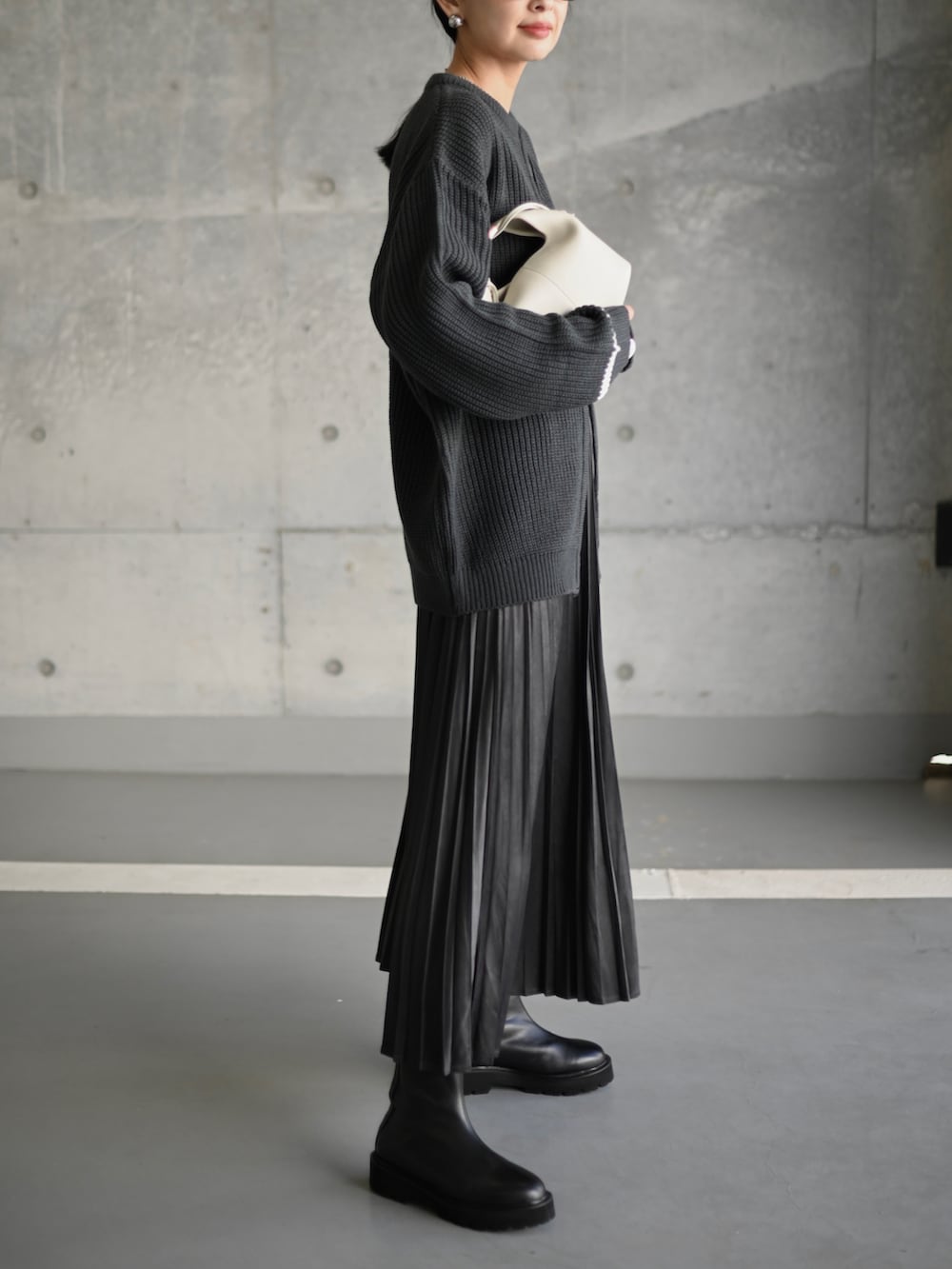 グレー系のスカート、ブラック系のブーツ、ホワイト系のショルダーバッグを着用したレディースの秋コーディネートの3枚目の写真