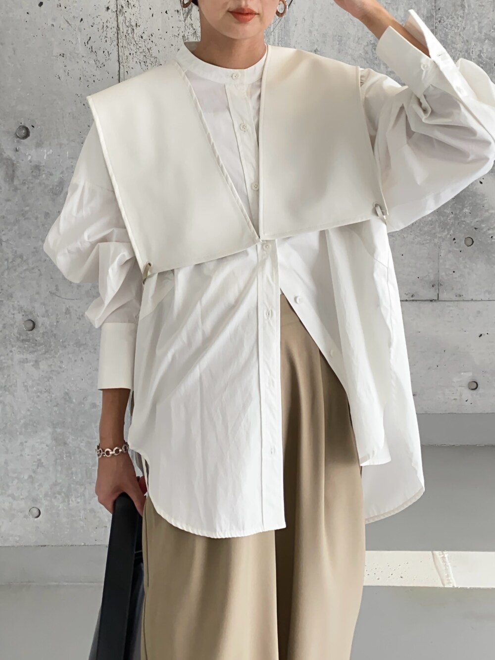 ホワイト系のベスト、ブラック系のブーツ、ブラック系のショルダーバッグを着用したレディースの春コーディネートの2枚目の写真