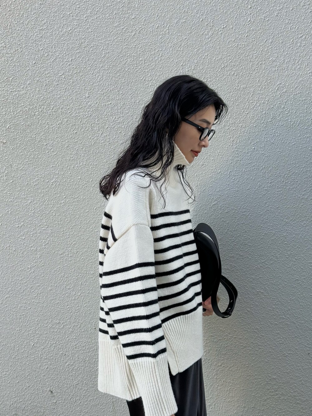 ホワイト系のニット/セーター、ブラック系のスカート、ブラック系のスニーカーを着用したレディースの冬コーディネートの3枚目の写真