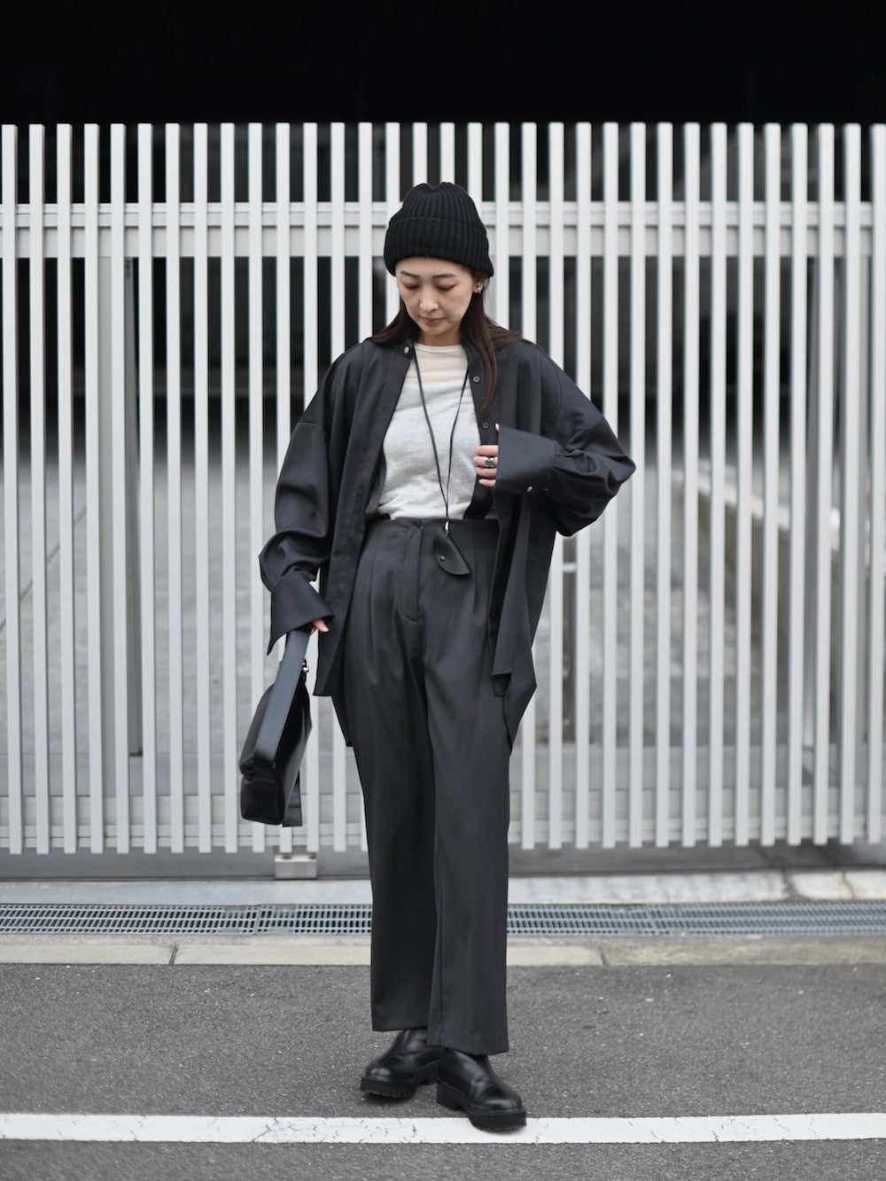 グレー系のシャツ/ブラウス、グレー系のスラックス、ブラック系のショルダーバッグを着用したレディースの冬コーディネートの2枚目の写真